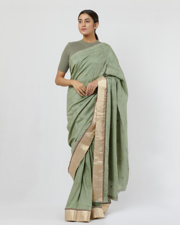 Sage green soft tussar sari with loops detail at the shoulder and pallu and a gold silk tissue border at the skirt adorned with hand embroidered butis all over
