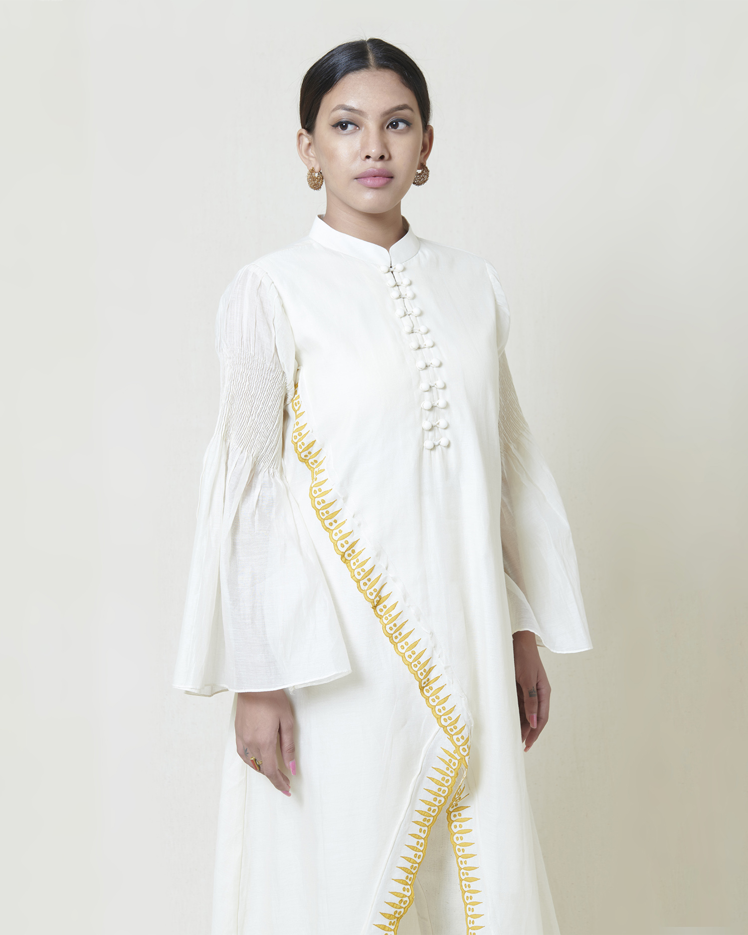 Ivory kora chanderi cross over kurta layered in mulmul with yellow applique and cutwork detailing accentuated with flared pintucked sleeves
