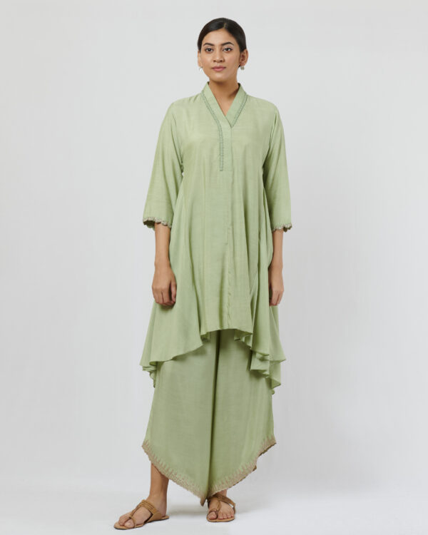 Soft mint highlow tunic with hand thread embroidery detail at neckline paired with silver kanchi tissue applique and cut work detailed drape pants.